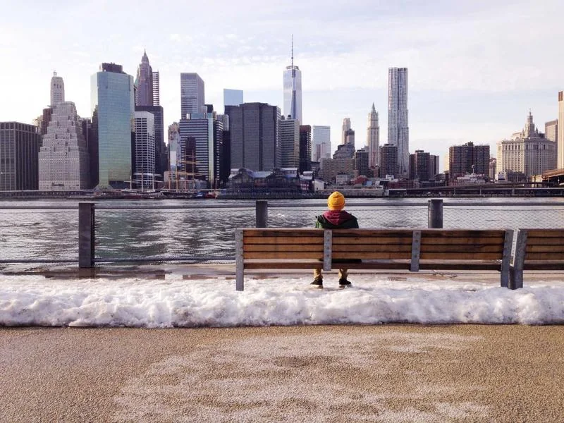 The New York City skyline seen across the water from a park bench